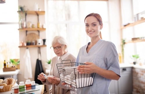 Standing near pensioner. Smiling medical attendant standing near pensioner wearing glasses