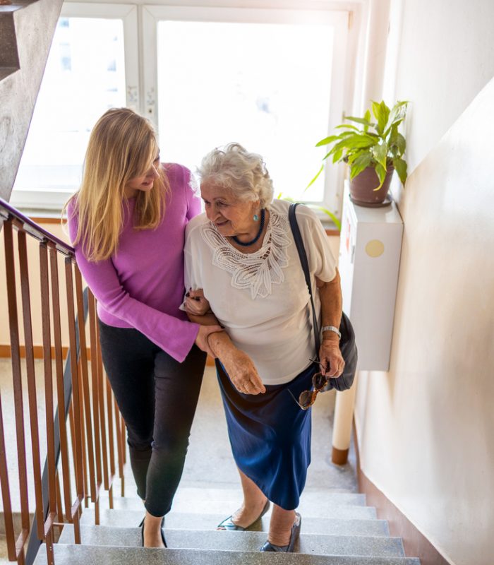 Caregiver helping senior woman climb staircase