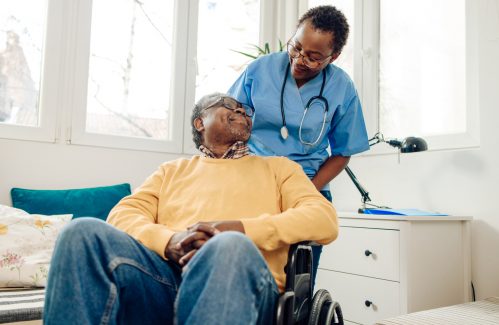 African American senior man in a wheelchair having support from his home caregiver.
